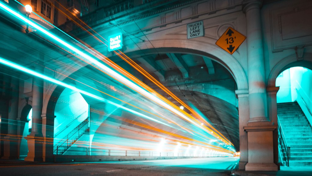 Traffic seen as streaks of colorful light going through a tunnel at night.