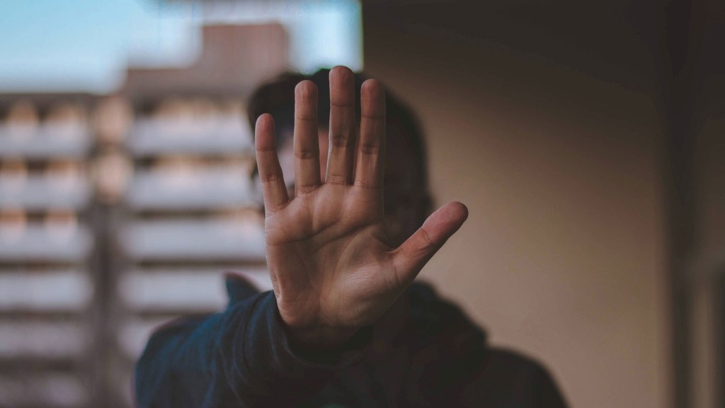 A person holds their hand up in front of their face